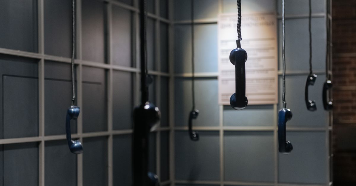 Artistic display of hanging vintage telephone receivers in a gallery. Unique and thought-provoking.
